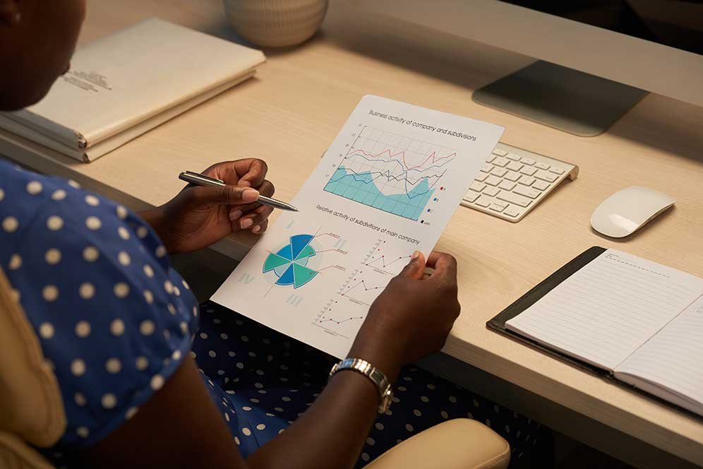 Businesswoman analyzing data graphs and charts at her desk.