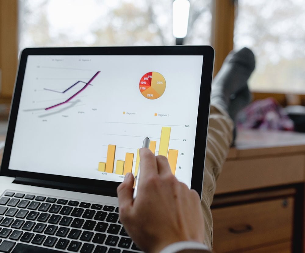 Person analyzing data on a laptop screen with graphs displayed.