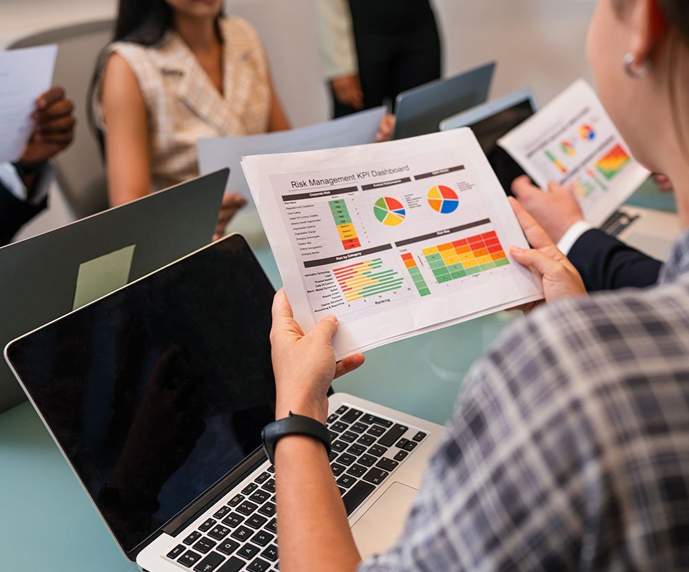 Business professionals reviewing a risk management kpi dashboard on paper in a meeting.