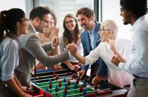 A group of colleagues enjoying a foosball game in an office setting, showcasing team bonding and a joyful atmosphere.