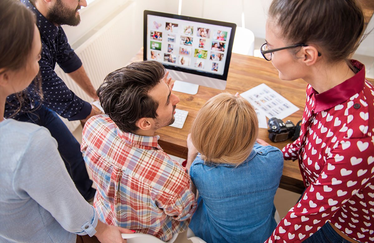 A group of people looking at a computer screen displaying a photo gallery.