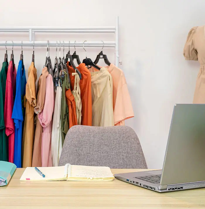 Online female clothes shop with laptop, notebook, document file on desk and casual cloth