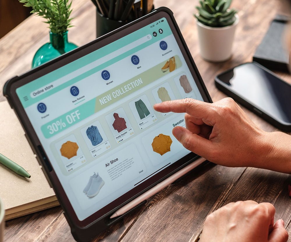 Person browsing an online store on a tablet featuring new clothing collection.