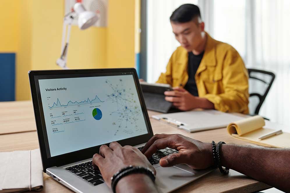 Man analyzing visitor activity data on his laptop in a modern office environment.